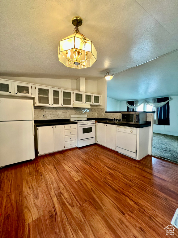 Kitchen featuring white cabinetry, dark wood-type flooring, white appliances, and hanging light fixtures