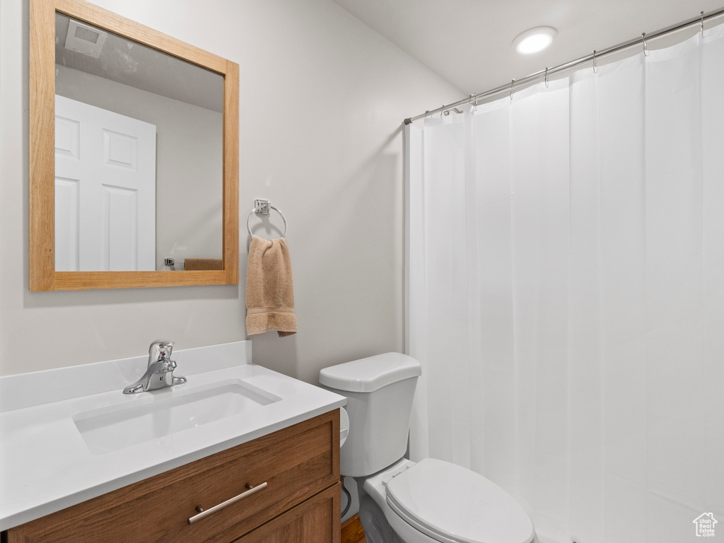 Bathroom featuring toilet, walk in shower, and vanity