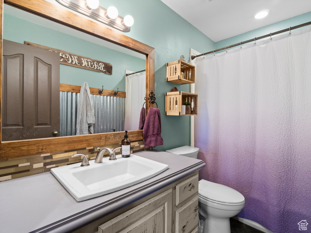 Bathroom with vanity, toilet, and backsplash