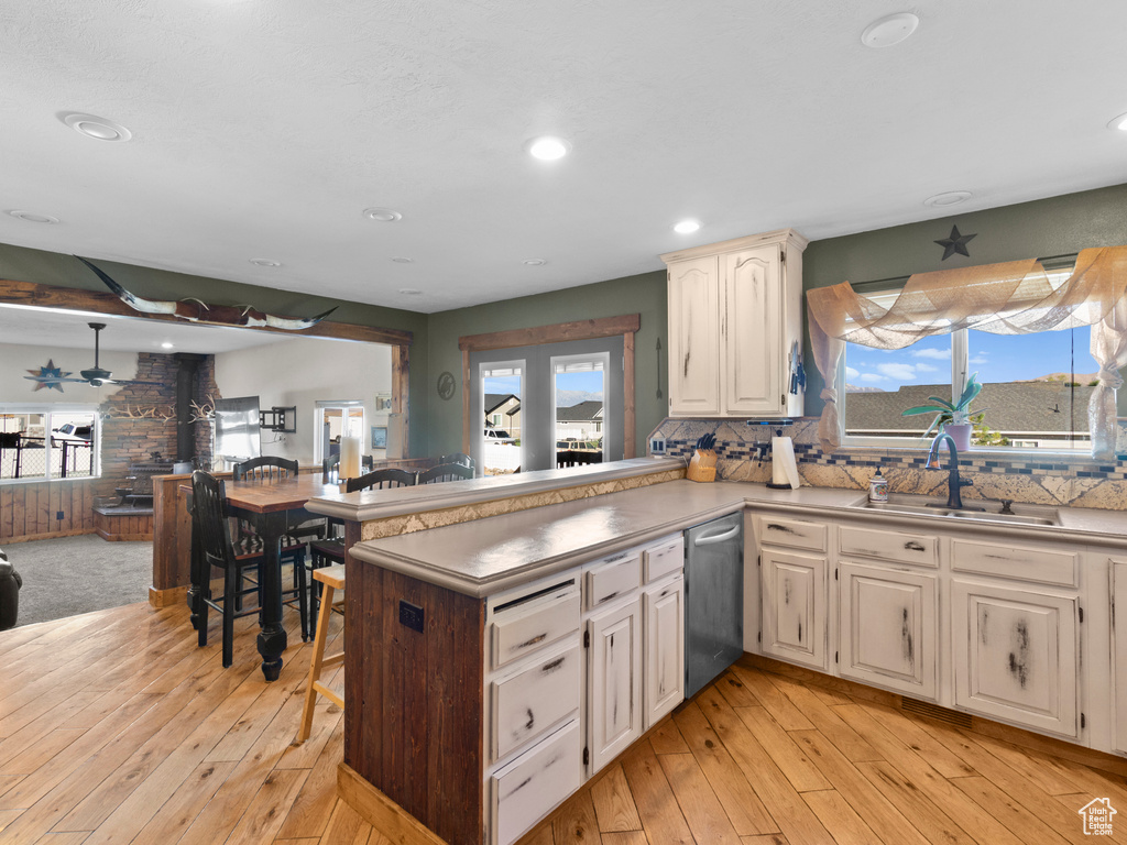 Kitchen with a wealth of natural light, sink, light hardwood / wood-style flooring, and kitchen peninsula