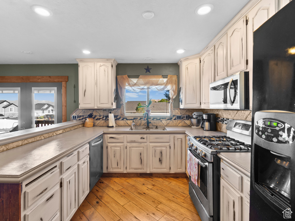 Kitchen featuring a wealth of natural light, sink, appliances with stainless steel finishes, and light hardwood / wood-style floors