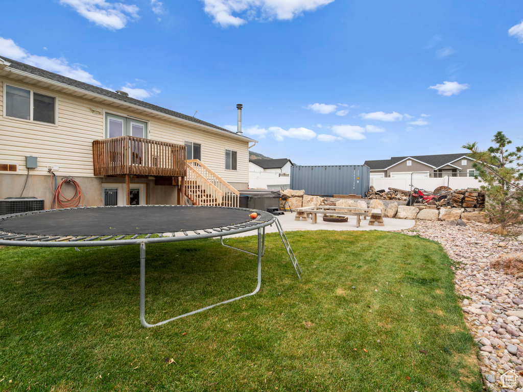 View of yard with a trampoline, a deck, and a patio