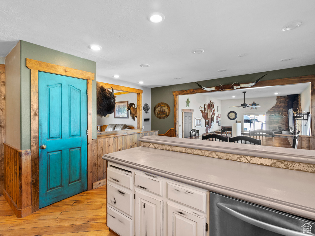 Kitchen with ceiling fan, light hardwood / wood-style flooring, stainless steel dishwasher, and white cabinets