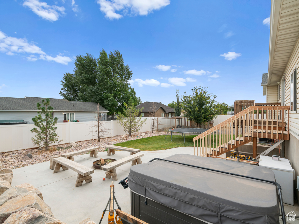 View of patio / terrace featuring a hot tub, a trampoline, and a deck