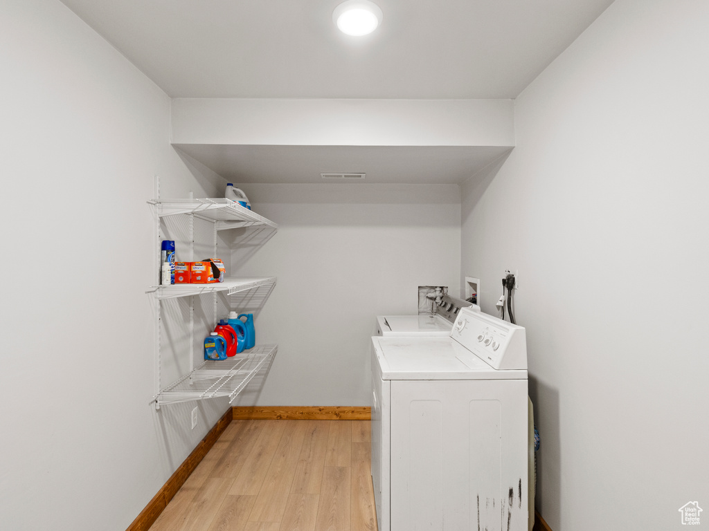 Clothes washing area featuring separate washer and dryer and light wood-type flooring