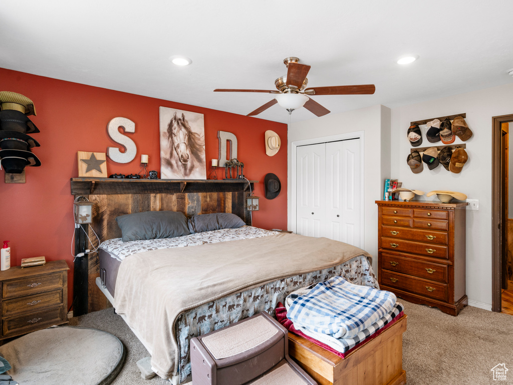 Carpeted bedroom featuring ceiling fan and a closet