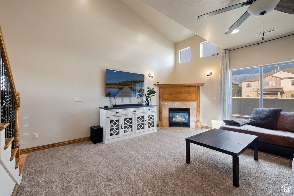 Living room with carpet, ceiling fan, high vaulted ceiling, and a fireplace