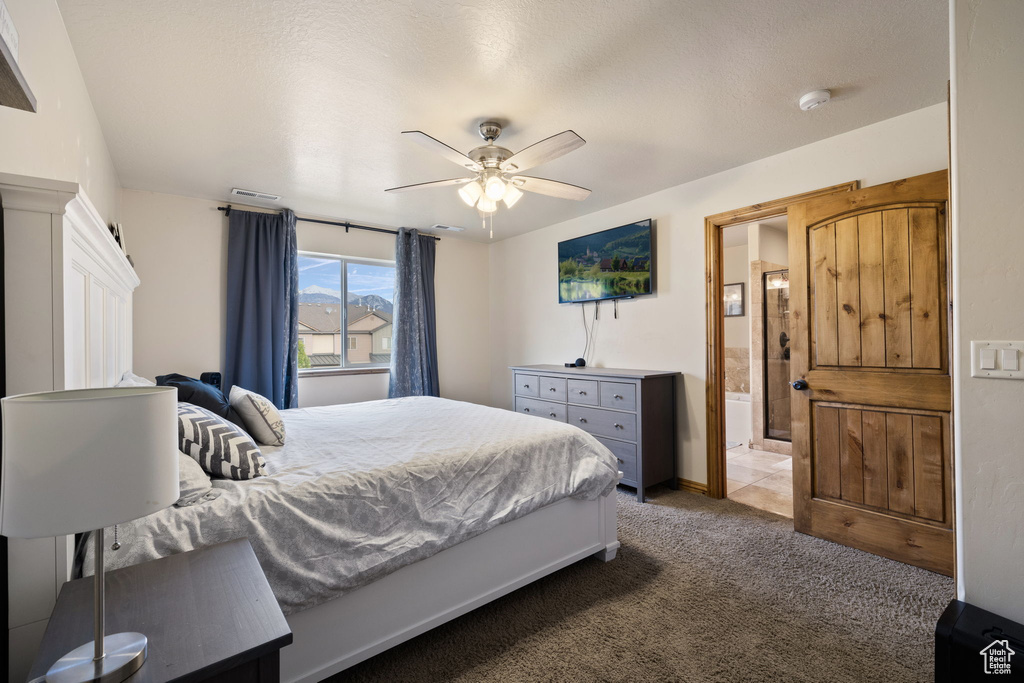 Bedroom with ensuite bath, light colored carpet, ceiling fan, and a textured ceiling