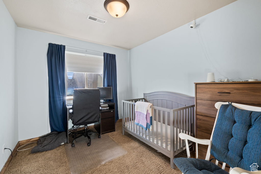 Carpeted bedroom featuring a nursery area