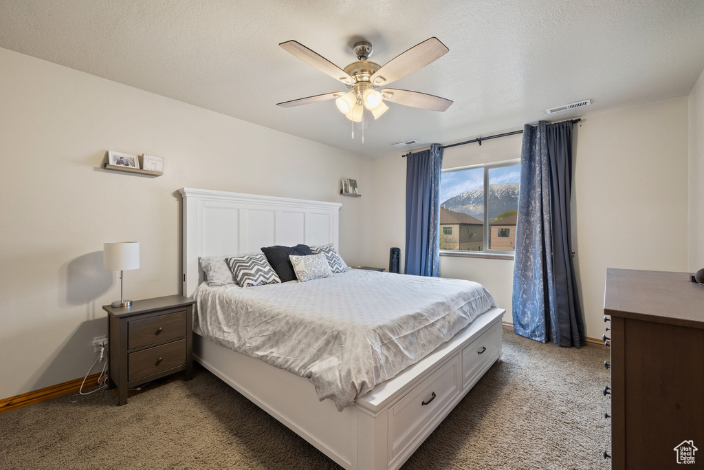 Bedroom featuring a textured ceiling, ceiling fan, and carpet flooring