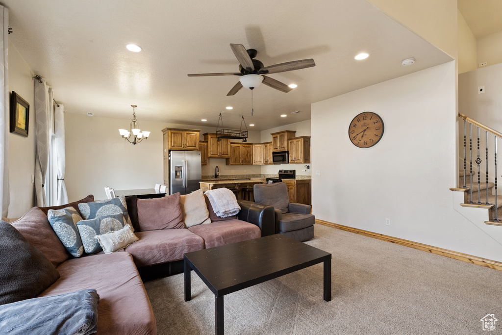 Carpeted living room with ceiling fan with notable chandelier and sink