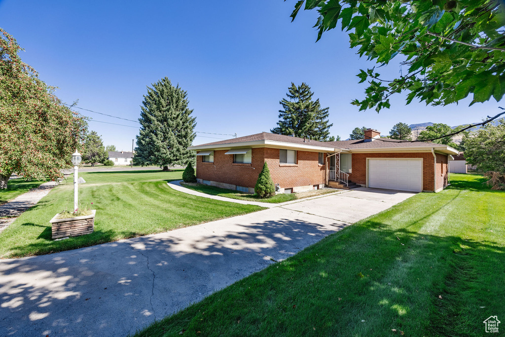 Ranch-style house with a garage and a front lawn