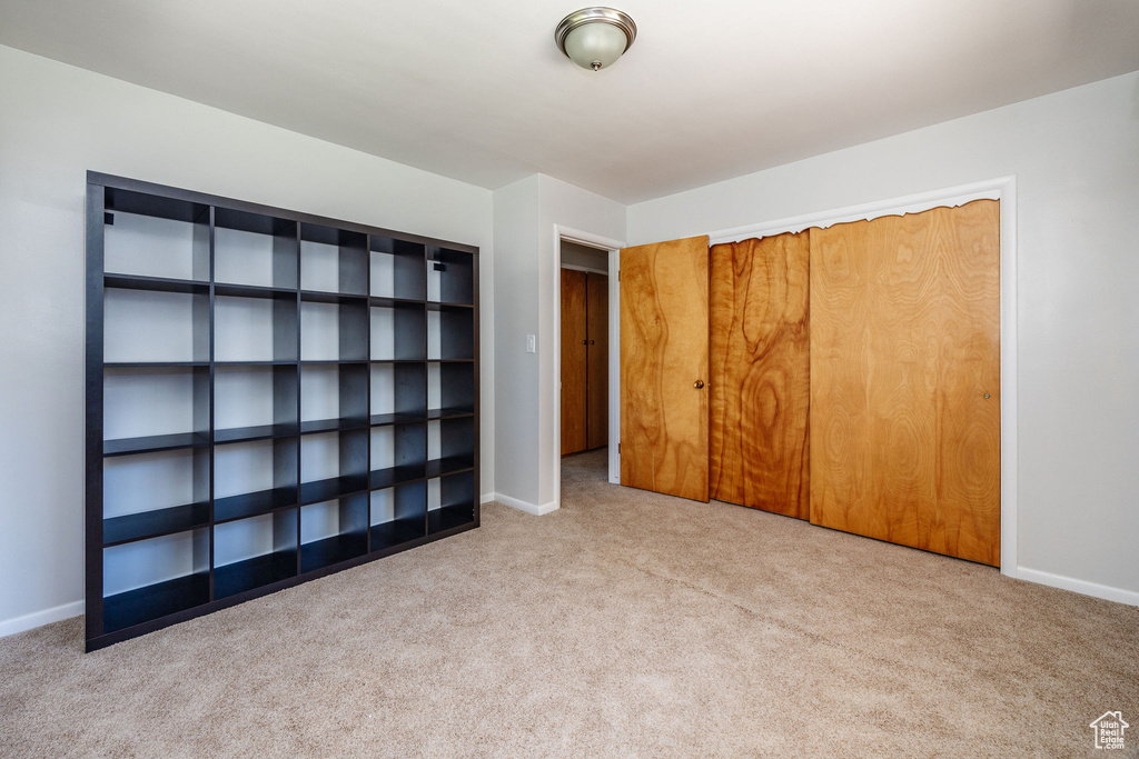 Unfurnished bedroom featuring light carpet and a closet