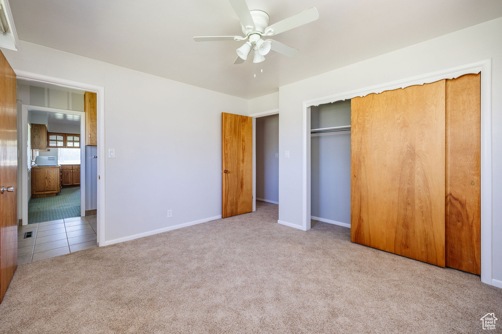 Unfurnished bedroom with a closet, ceiling fan, and light carpet