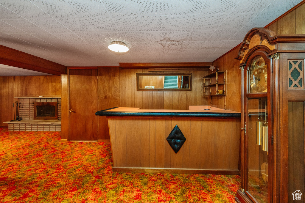 Kitchen with a brick fireplace, wooden walls, and carpet floors