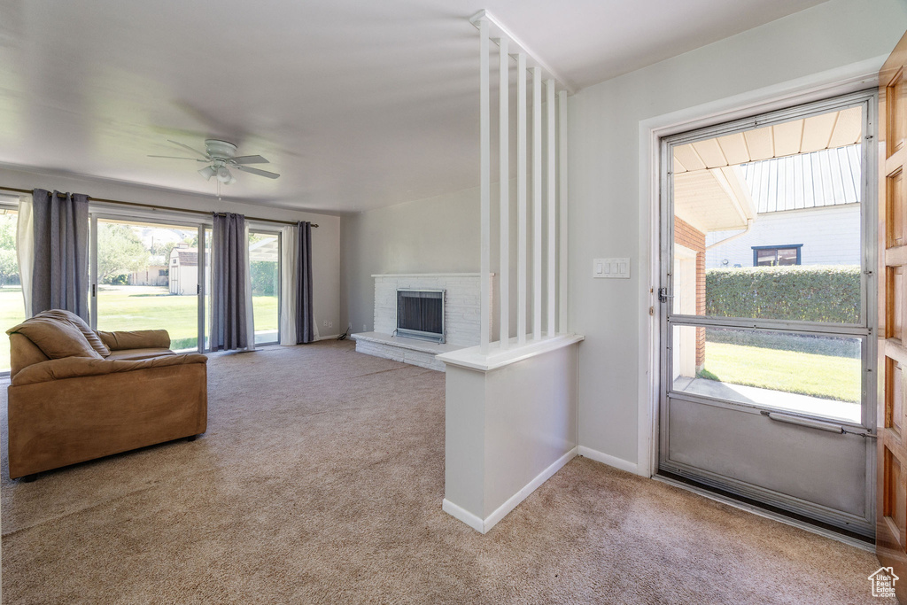 Living room featuring ceiling fan, light carpet, and a brick fireplace