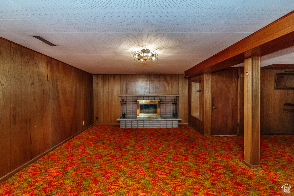 Basement featuring dark colored carpet and wooden walls