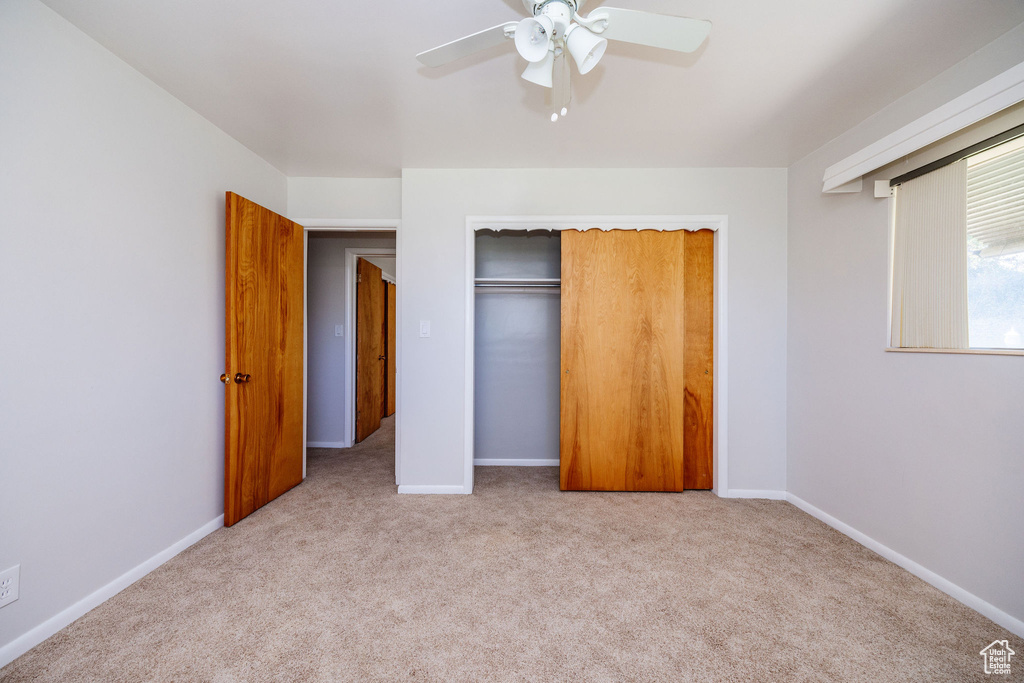 Unfurnished bedroom featuring a closet, ceiling fan, and light carpet