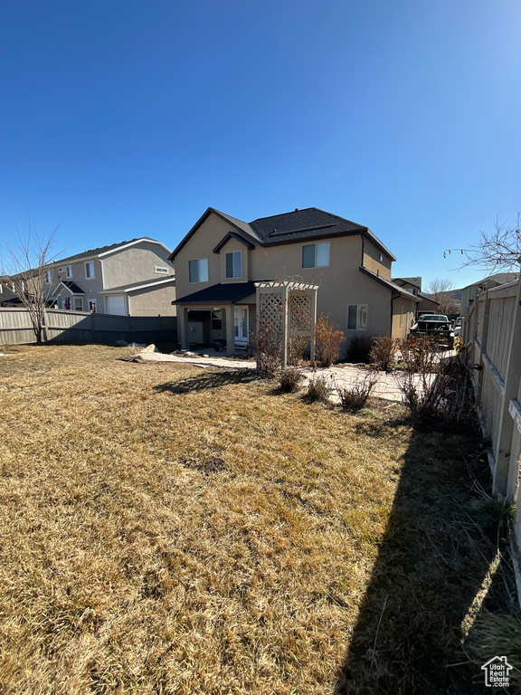 Back of property featuring a lawn and a pergola