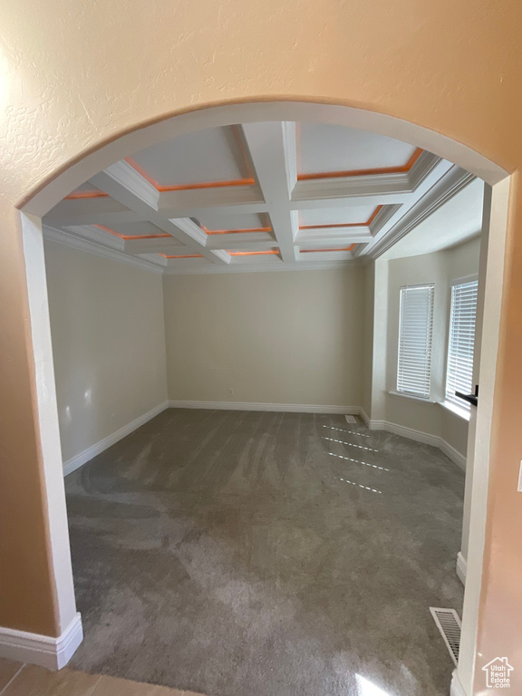 Carpeted empty room featuring ornamental molding, coffered ceiling, and beam ceiling