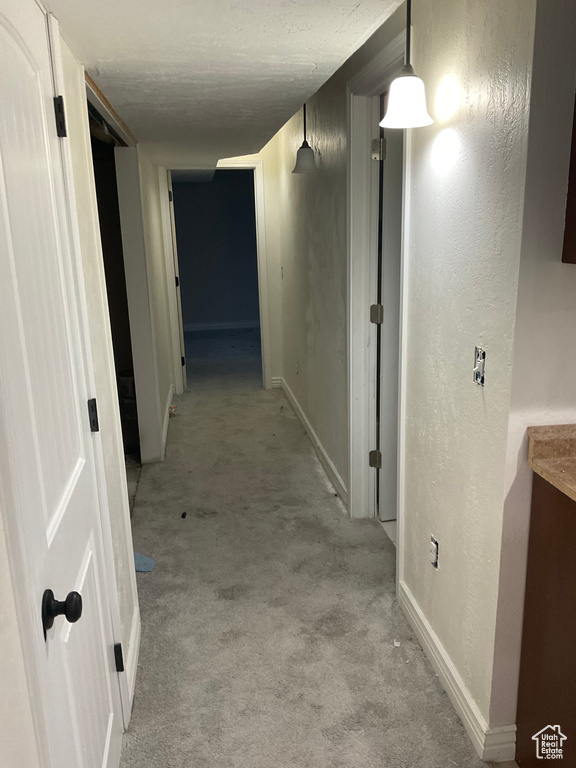 Hallway featuring a textured ceiling and light colored carpet