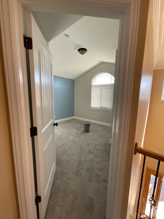 Carpeted spare room featuring lofted ceiling