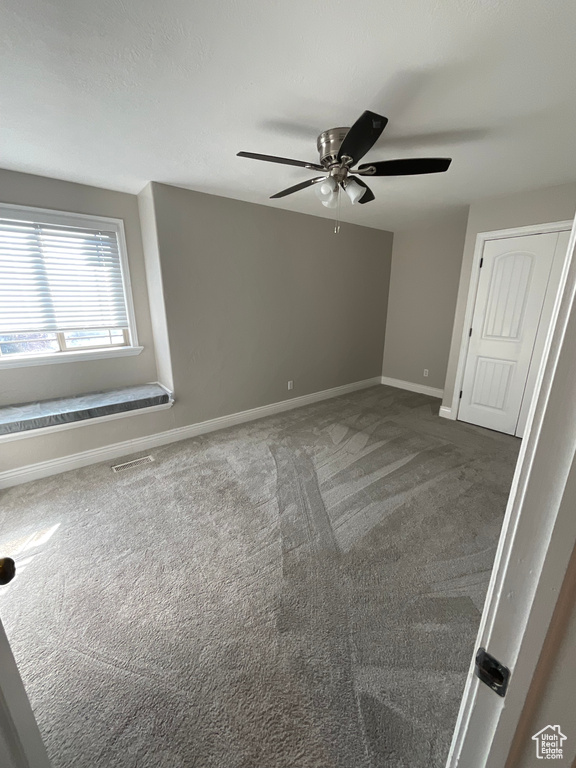 Spare room with ceiling fan and carpet floors