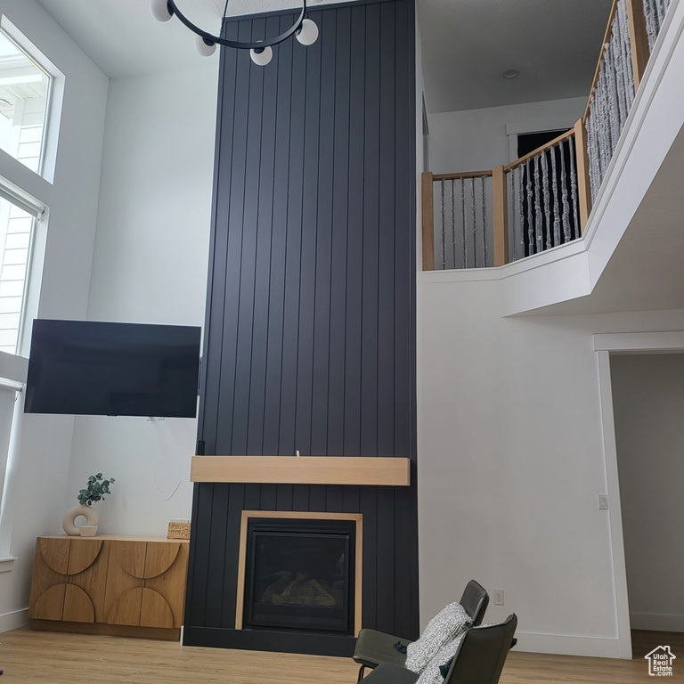 Living room with a towering ceiling, wood-type flooring, and a fireplace