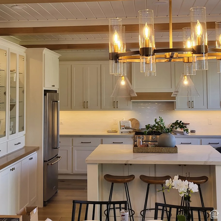 Kitchen featuring hanging light fixtures, high end fridge, light hardwood / wood-style flooring, a center island, and a breakfast bar