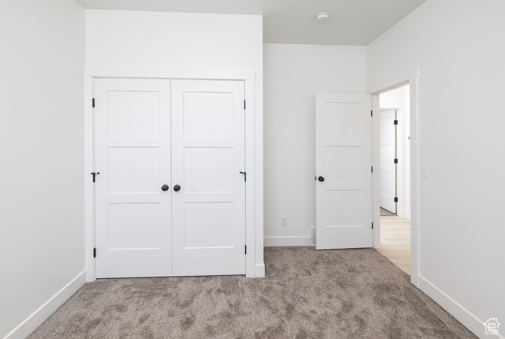 Unfurnished bedroom featuring light colored carpet and a closet