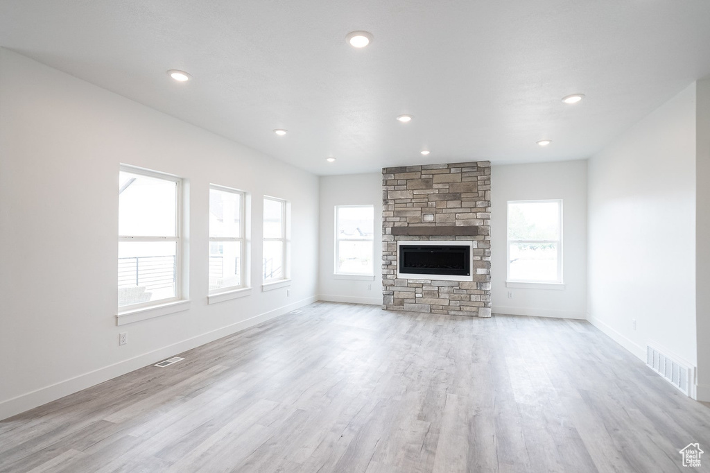 Unfurnished living room featuring a stone fireplace and light hardwood / wood-style flooring