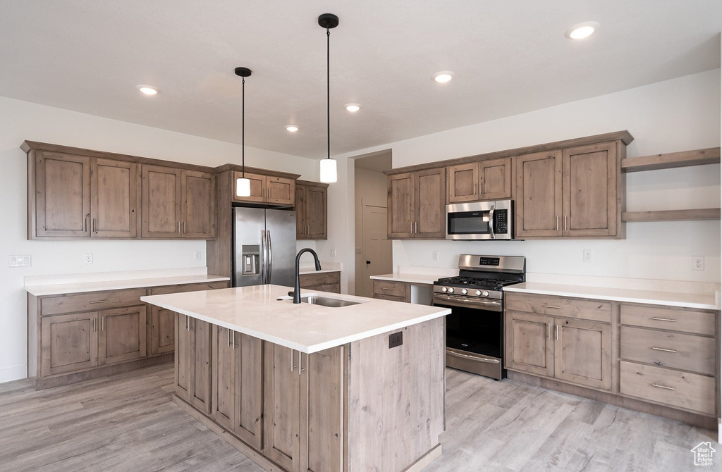 Kitchen featuring pendant lighting, a center island with sink, appliances with stainless steel finishes, and sink