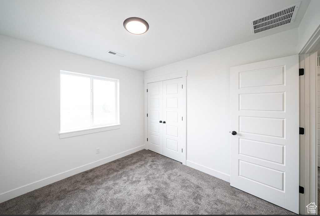 Unfurnished bedroom with light colored carpet and a closet