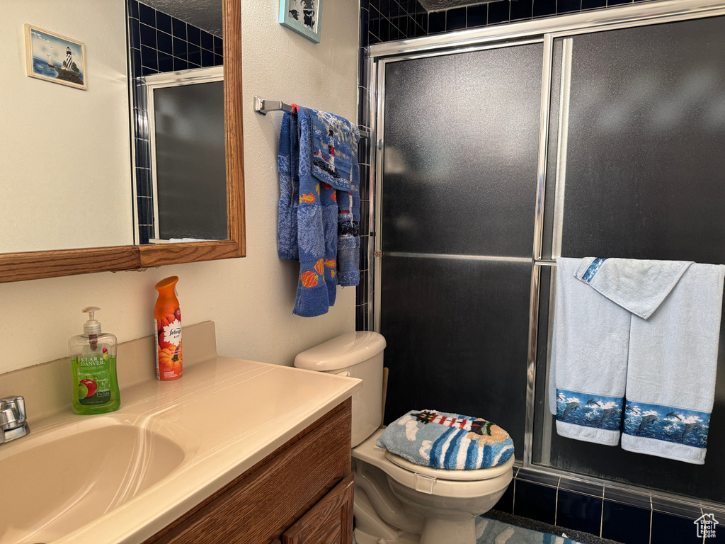 Bathroom with tile patterned flooring, toilet, a shower with door, and vanity