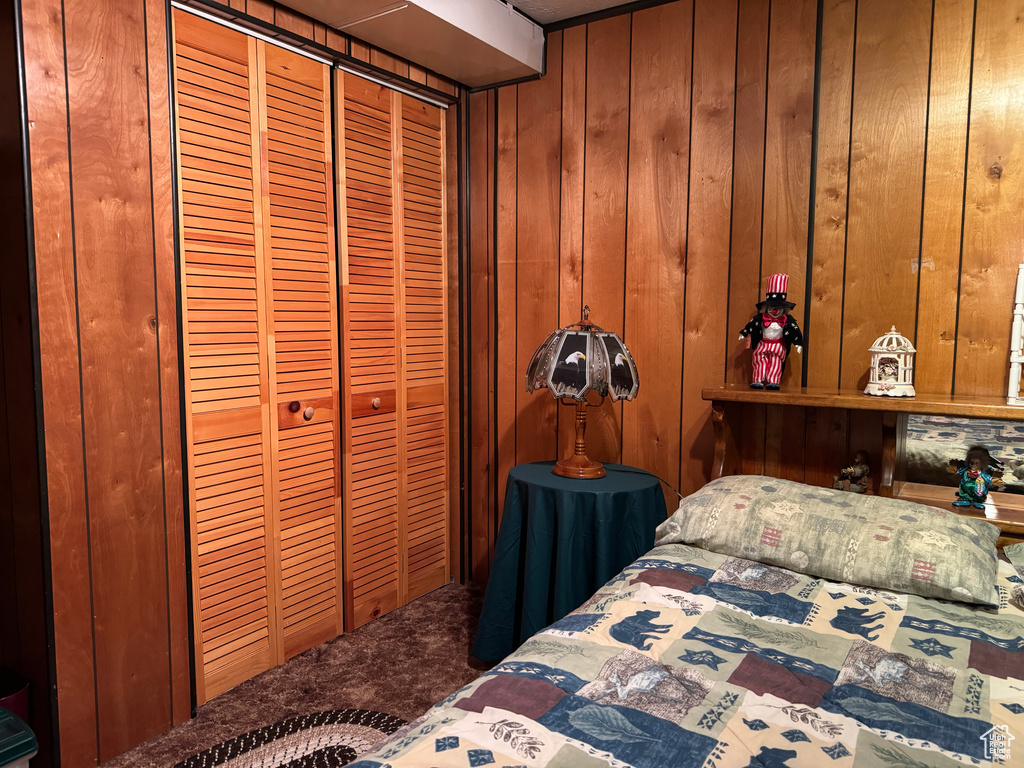 Carpeted bedroom featuring wood walls