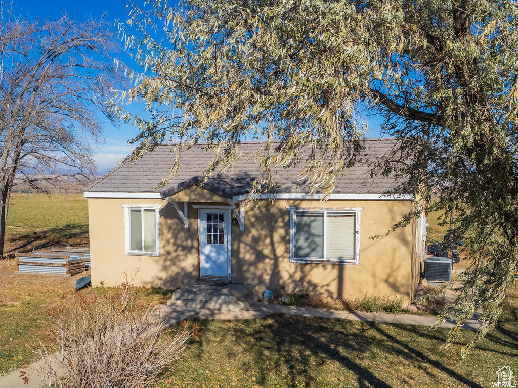 Bungalow-style home featuring central AC unit, a front yard, and a patio area