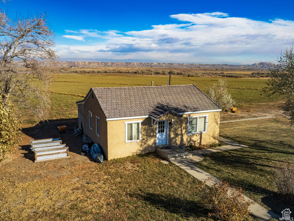 View of front of home with a front yard, a mountain view, and a rural view