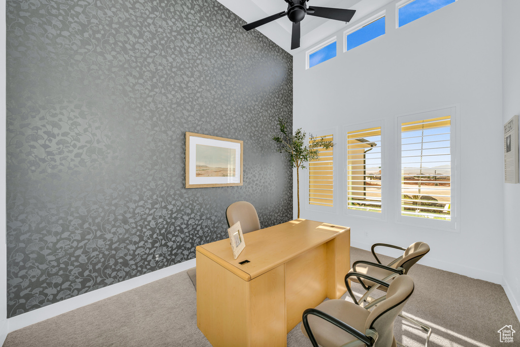 Carpeted office space featuring ceiling fan and a high ceiling