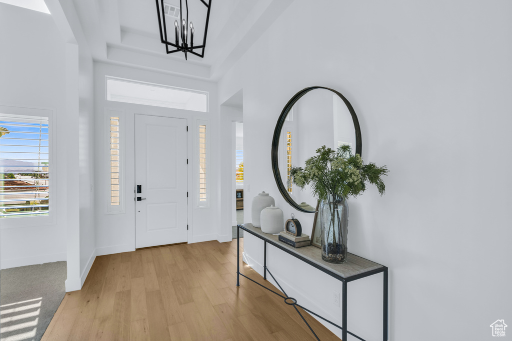 Foyer with a high ceiling, light hardwood / wood-style floors, and a chandelier