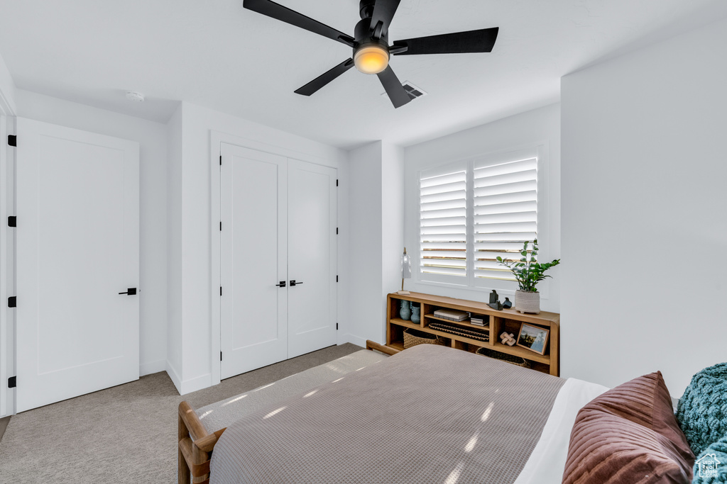 Carpeted bedroom with a closet and ceiling fan