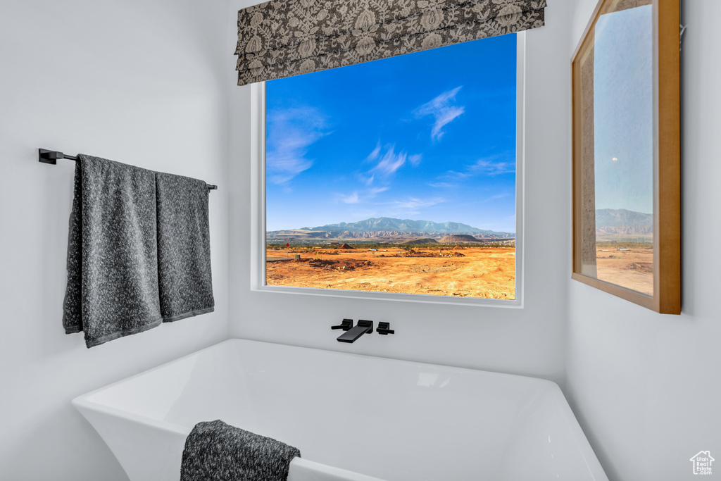 Bathroom featuring a tub to relax in, a mountain view, and a healthy amount of sunlight