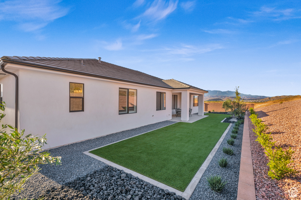 Rear view of house with a patio, a yard, and a mountain view