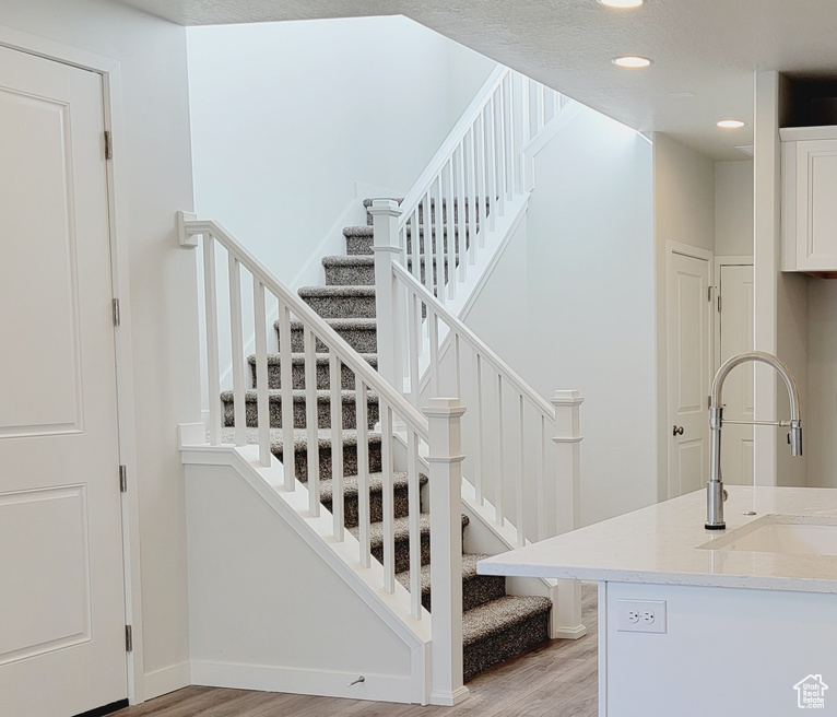 Stairs with sink, wood-type flooring, and a textured ceiling