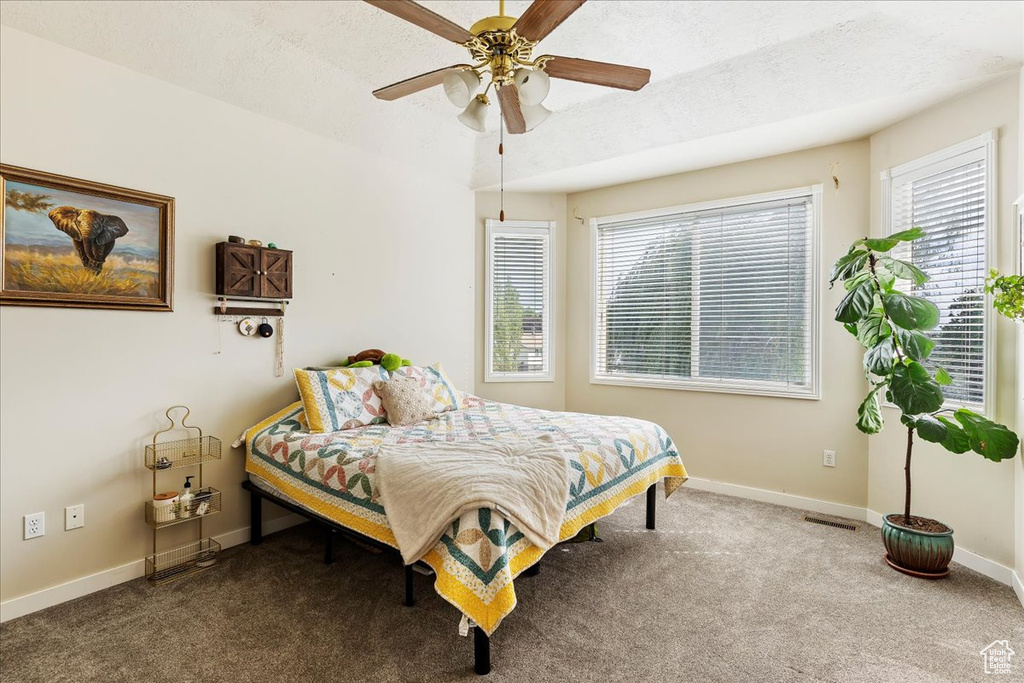 Carpeted bedroom featuring a textured ceiling and ceiling fan