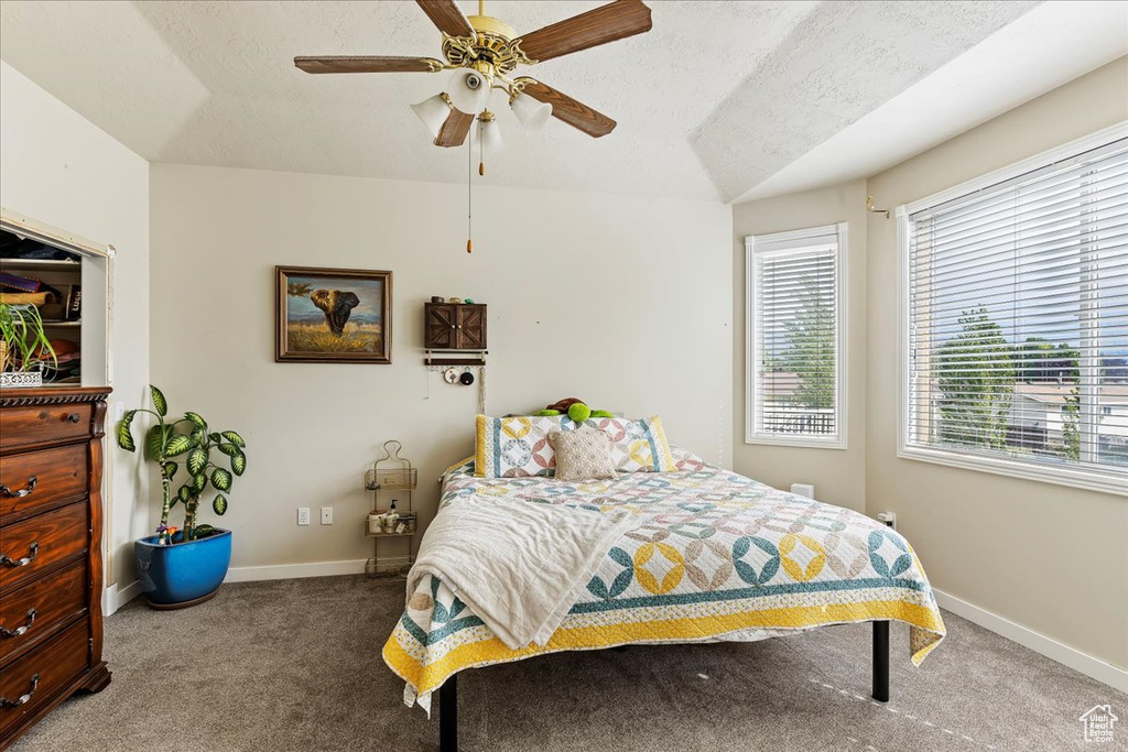 Carpeted bedroom featuring ceiling fan and a textured ceiling