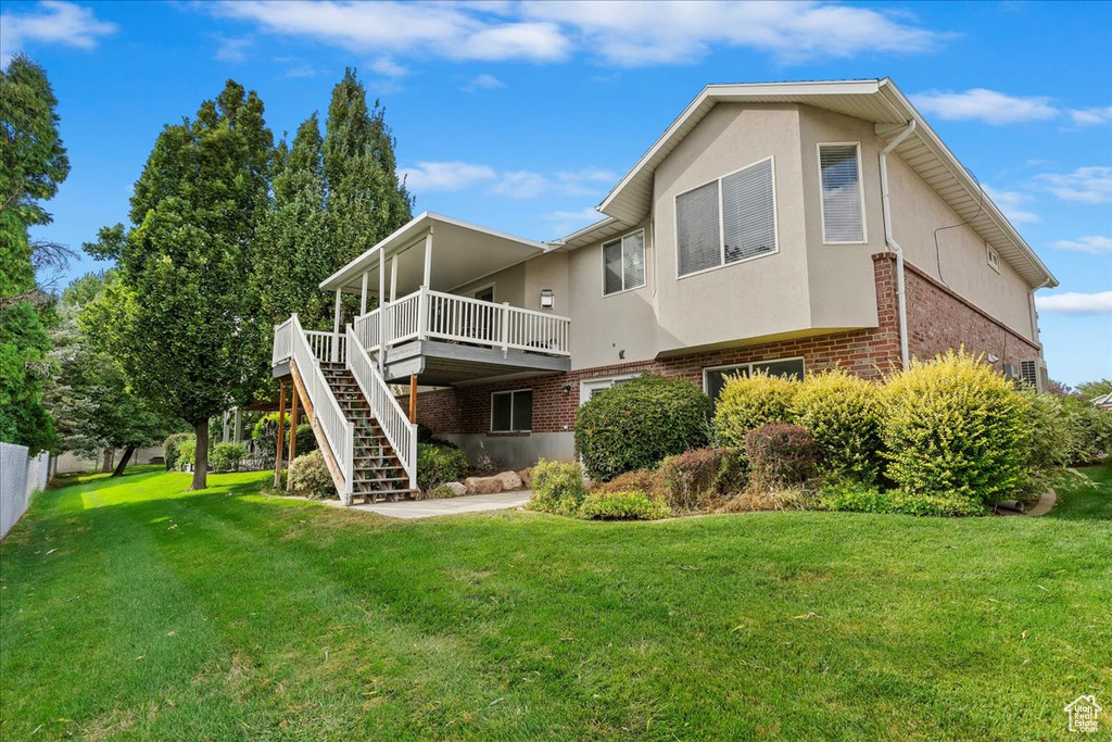 Rear view of house featuring a yard and a wooden deck