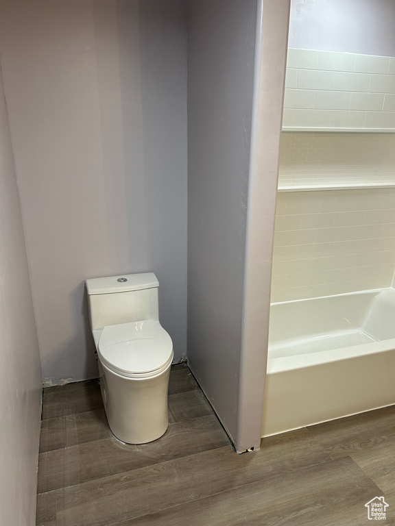 Bathroom with wood-type flooring, toilet, and a bathing tub