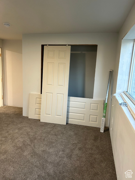 Unfurnished bedroom with dark carpet