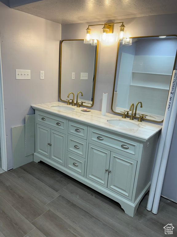 Bathroom with hardwood / wood-style flooring, vanity, and a textured ceiling