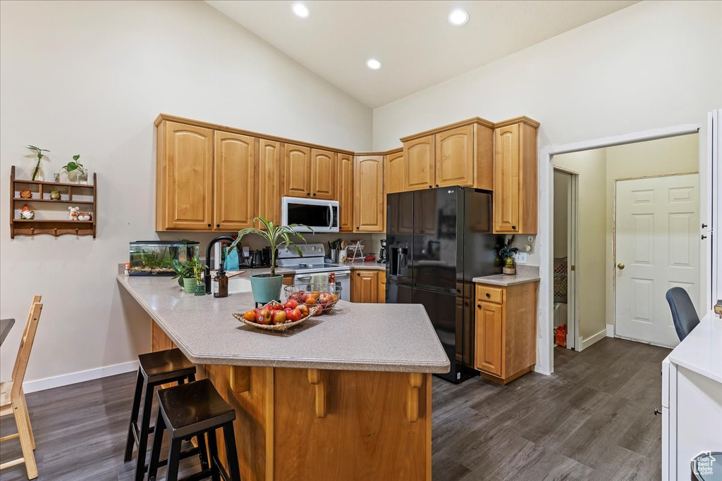 Kitchen with a breakfast bar, kitchen peninsula, black fridge with ice dispenser, white electric range oven, and dark hardwood / wood-style flooring